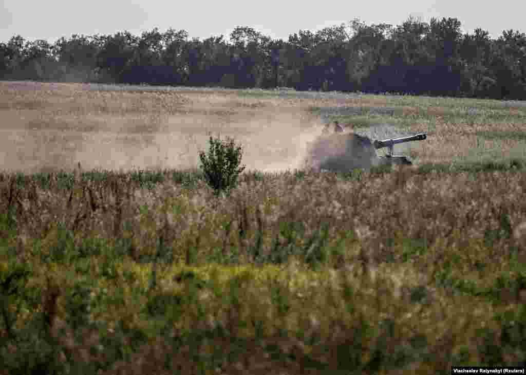 A Ukrainian M109 self-propelled howitzer roars through farmland in the Donetsk region on August 7. In the Zaporizhzhya region, Kyiv's forces ran into what experts described as a meat-grinder of Russian fortifications -- layers of trenches, minefields, barbed wire, anti-tank defenses, pillboxes -- that forced Ukrainian units into narrow strips of land where they were punished by Russian artillery.