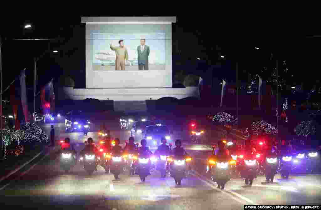 A joint limousine motorcade snakes through the capital decorated with Russian flags and pictures of Putin. &nbsp;