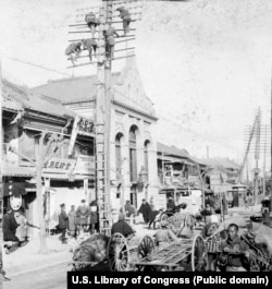 Workers construct telegraph poles above a busy street in Tokyo in 1905.