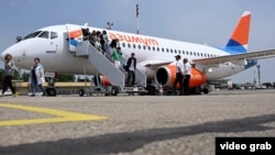 Passengers on the inaugural flight were greeted by a media scrum and hundreds of protesters.