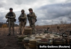 Бійці спецпідрозділу з розмінування Нацполіції стоять біля знешкоджених протитанкових мін під час операції з розмінування біля міста Ізюм, Харківська область, Україна, 24 жовтня 2023 року (ілюстраційне фото)
