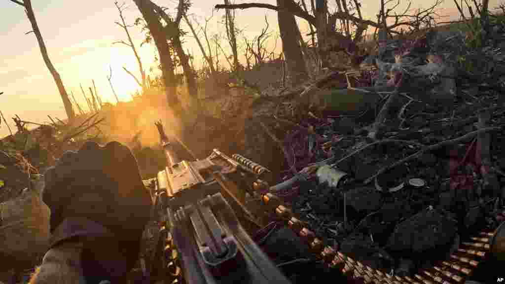 A member of Ukraine's 3rd Assault Brigade fires a machine gun toward Russian positions near Andriyivka on August 27 in this image captured from a video. The Associated Press had an intimate glimpse into the Ukrainian counteroffensive with the use of helmet cameras and drone video.