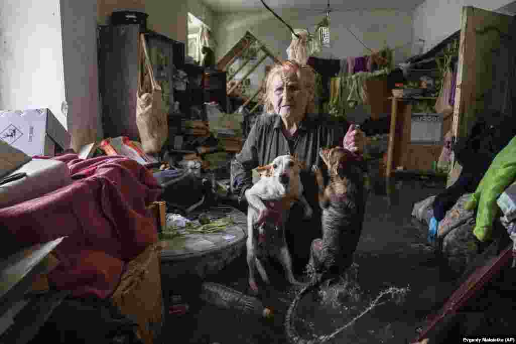 Local resident Tetyana holds her pets, Tsatsa and Chunya, above the floodwater as she stands inside her house in the Ukrainian port city of Kherson on June 6. 