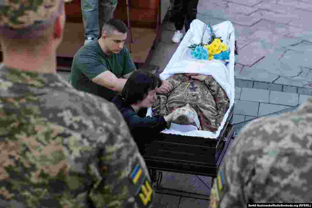 The grieving mother of Serhiy Konoval kneels at her son's coffin.