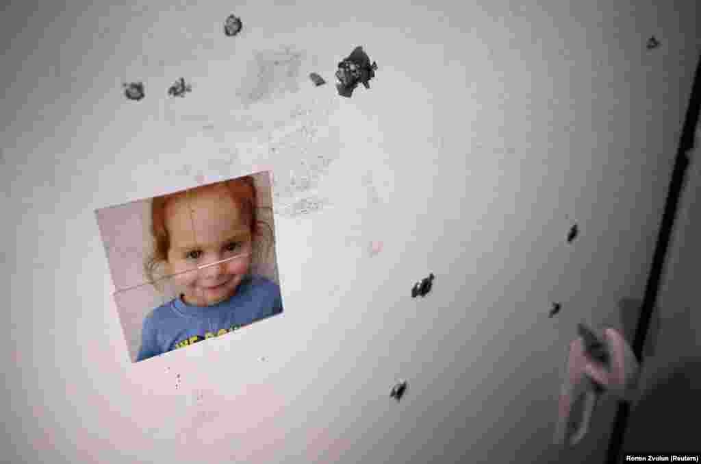 На двери обстрелянного дома приклеена фотография девочки, похищенной 7 октября боевиками радикальной группировки ХАМАС (признанной США и ЕС террористической организацией) из израильского поселения Нир-Оз. 21 ноября, 2023.&nbsp;(REUTERS/Ronen Zvulun )
