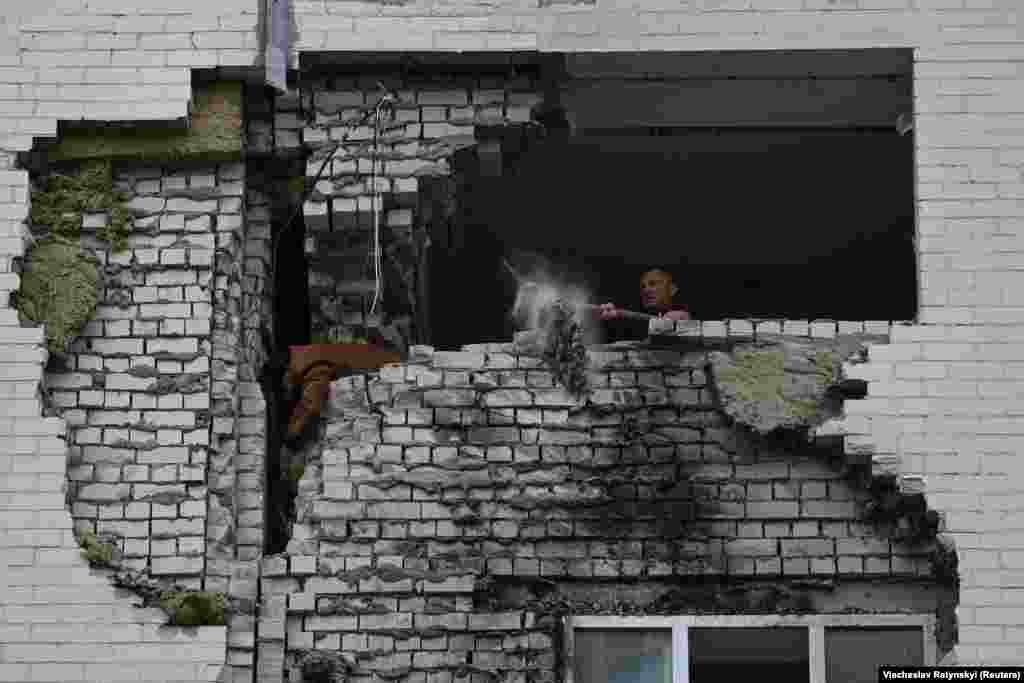 A local man clears the wreckage from his flat after it was struck by Russian missile fragments. 