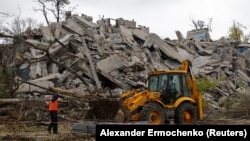 An excavator operates on the ruins of a building destroyed in the course of the Russian invasion in Mariupol, in Russian-controlled Ukraine.