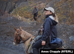A shepherd and his dog pause to watch Ididze lead her horses toward the Abano Pass.