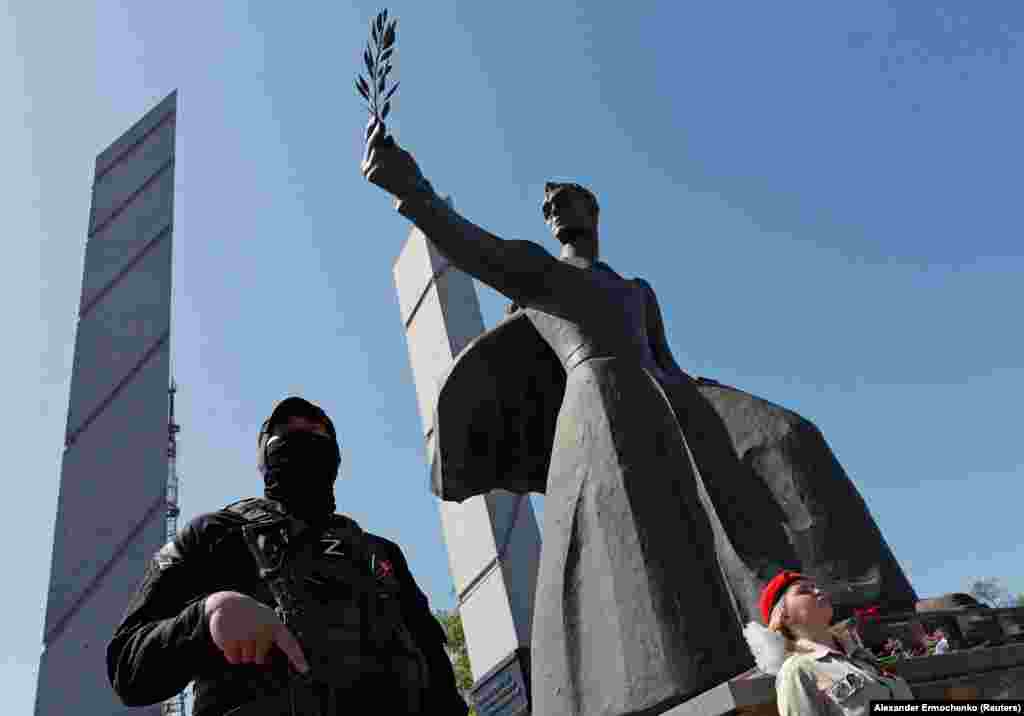 A separatist fighter keeps an eye on the crowd under the Liberation Memorial in Mariupol.