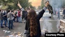 یکی از زنان ایرانی به رسم اعتراض حجاب خود را در جریان مظاهرات تهران برداشته است