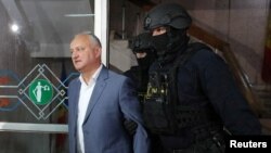 Ex-President Igor Dodon is escorted by law enforcement officers before a court hearing in Chisinau in May.