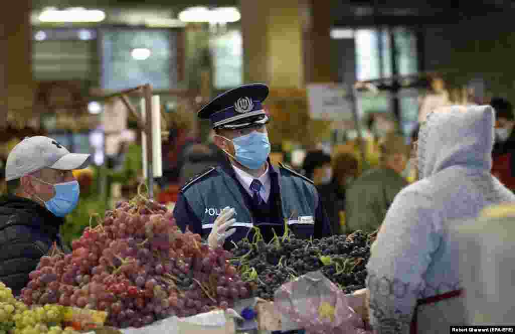 A policeman speaks to fruit sellers at a market in Bucharest on October 16. President Klaus Iohannis suggested restrictive new measures are likely. "Whether we are talking about the green certificate or other measures to reduce mobility and human interaction, we must not waste any more time...no matter how unpopular it may seem," he said on October 19. 