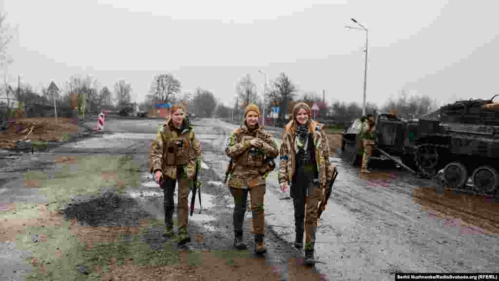 Armed volunteers from the Hospitallers Medical Battalion walk through the village.