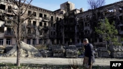 Орусия басып алган Мариуполдо талкаланган үй жана анын жанынан өтүп бараткан тургун. Ноябрь, 2022-жыл. 