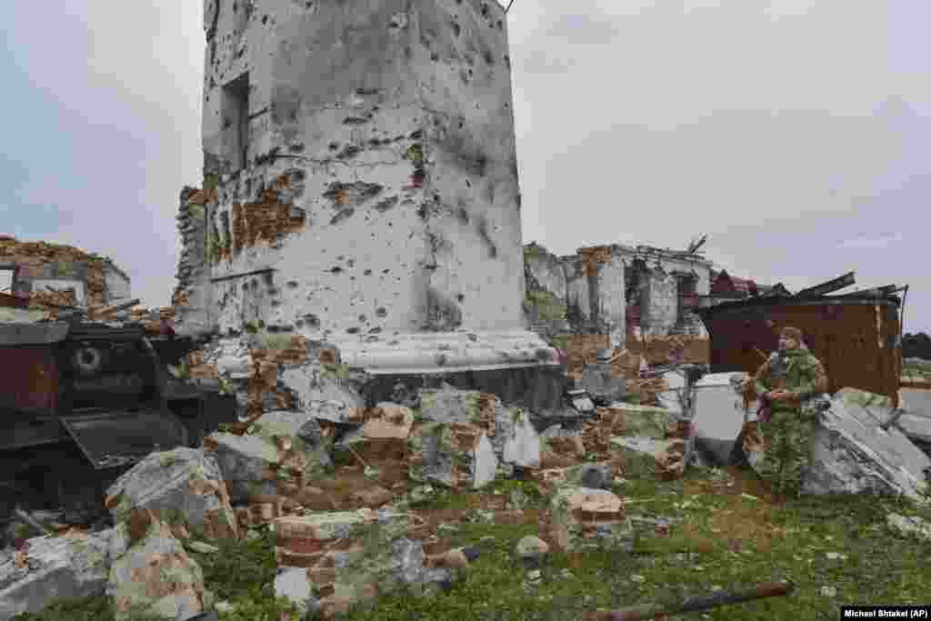 Украинский солдат у основания поврежденного 180-летнего маяка на Змеином острове. На фотографиях 2009 года видно здание вокруг этого маяка, которое было разрушено во время боев за остров. 