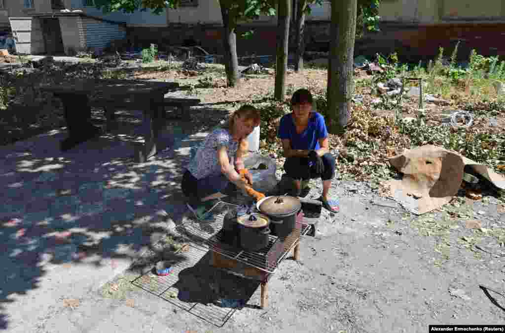 Local residents cook food on an open fire.