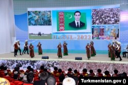 Танцы на сцене на фоне портрета президента Туркменистана Сердара Бердымухамедова в День урожая
