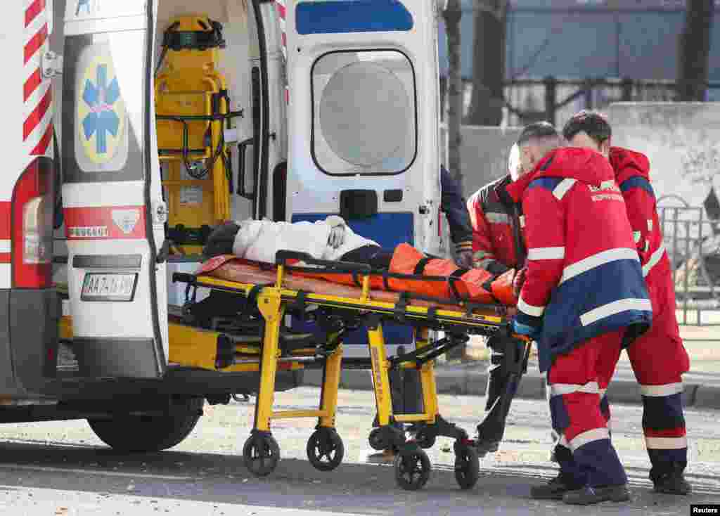 Medical personnel transport a wounded woman to an ambulance after the recent shelling.