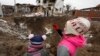 Діти дивляться на воронку, яка залишилася внаслідок російського ракетного удару в селищі міського типу Глевасі на Київщині, 26 січня 2023 року (ілюстраційна світлина)