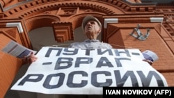 Vladimir Ionov holds a banner reading "Putin -- Enemy of Russia" during a demonstration in Moscow in July, 2013.