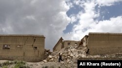 په ګیان ولسوالۍ کې یو کس په زلزله کې د زیانمنو کورونو تر څنګ تېرېږي - د جون ۲۳مې انځور.