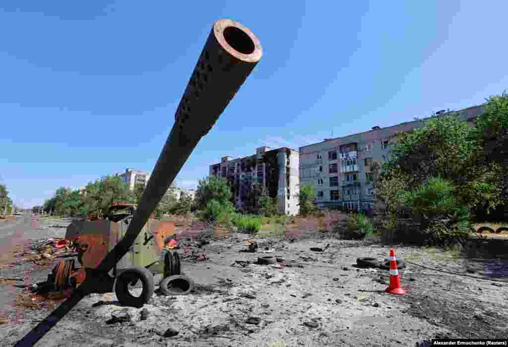 The remains of an MT-12 &quot;Rapira&quot; anti-tank gun near burned-out residential buildings.