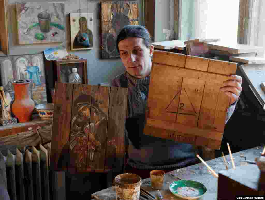 Ukrainian artist Oleksandr Klymenko shows one of his ammunition-box icons and part of a discarded ammo box he uses for his artwork at his Kyiv studio.