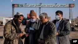د طالبانو د حکومت یو کارکوونکی په اسلام کلا کې د ایران پولې ته څېرمه د یو افغان وګړي پاسپورټ ګوري - پخوانی انځور.