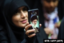 Iranka pokazuje masku svog telefona na kojoj se nalazi slika vrhovnog vođe ajatolaha Ali Hamneija. Mnogi upozoravaju da bi cenzura interneta koja se razmatra mogla povećati jaz između Iranaca i klerikalnog establišmenta.