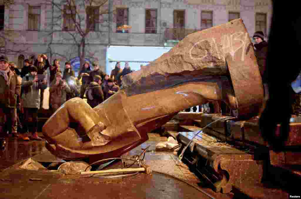 People surround a statue of Soviet state founder Vladimir Lenin, which was toppled by protesters during a rally organized by supporters of EU integration in Kyiv on December 8, 2013.