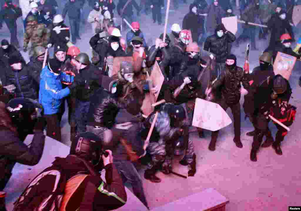 Pro-EU protesters clash with Ukrainian riot police during a rally near government administration buildings in Kyiv on January 19, 2014. Protesters attacked riot police with sticks and tried to overturn a bus blocking their path to parliament, as up to 100,000 Ukrainians massed in defiance of sweeping new laws aimed at stamping out antigovernment demonstrations.