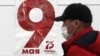 Чоловік у захисній масці на тлі агітаційного плакату з нагоди 75-ї річниці завершення Другої світової війни в Європі, Москва, 5 травня 2020 року