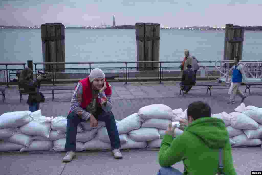 The Statue of Liberty is seen in the background as tourists from Russia pose for pictures on top of sand bags protecting Battery Park in Lower Manhattan, New York. 
