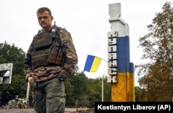 Український військовий біля знаку з написом «Куп’янськ» у відвойованому напередодні ЗСУ місті Куп’янську на Харківщині, 14 вересня 2022 року