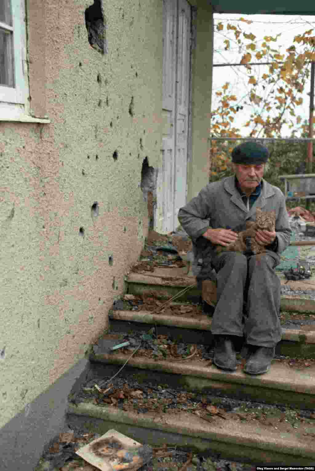 Житель Абхазии около прошитого пулями дома. Когда война затянулась и наступила зима, группы боевиков начали терроризировать сельскую местность в регионе, где наступило полное беззаконие.