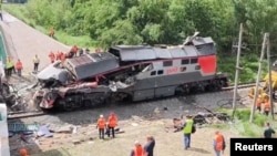 Emergency services work to remove a damaged locomotive after a road bridge collapsed onto railway tracks, derailing an approaching train in Russia's Bryansk region on June 1.