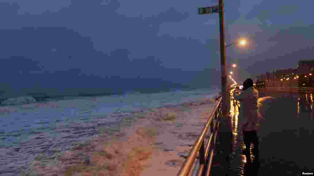 A woman takes a photo at Beach 98th street on the boardwalk at Rockaway Beach in the Queens borough of New York. 