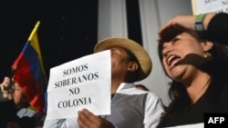Demonstrators hold a sign reading "We are sovereign, not colonies," as they shout slogans outside the British Embassy in Quito on August 15.