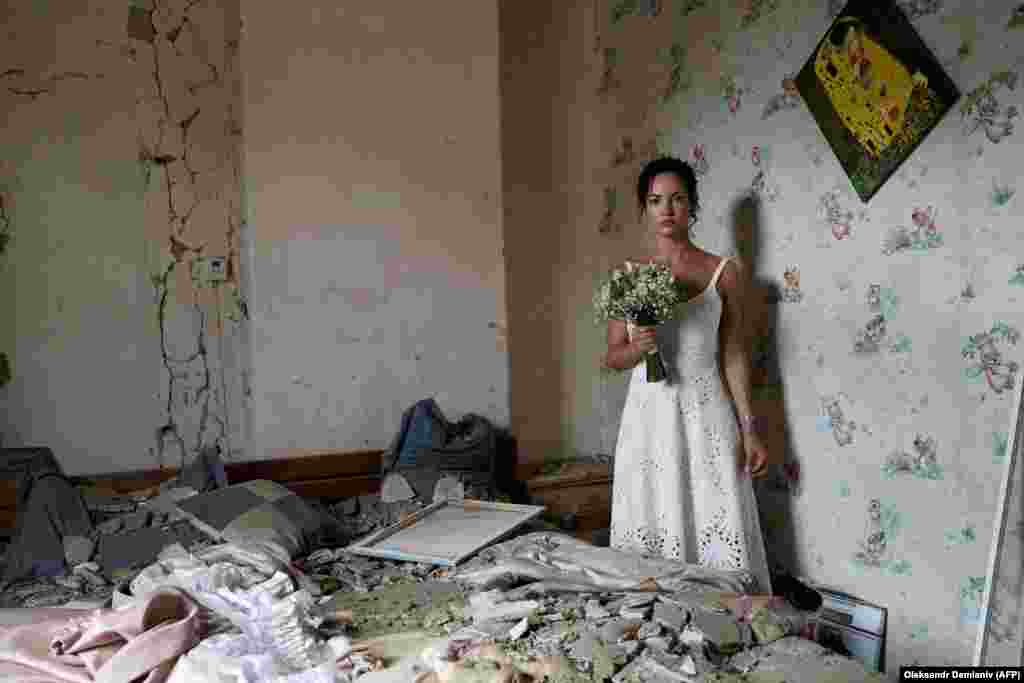 31-летняя Дарья Стенюкова позирует для свадебных фотографий в своей разбомбленной квартире в Виннице 16 июля. В преддверии свадьбы девушки российские войска обстреляли ракетами центр города, погибли 26 человек. Супруги были настроены решительно: "Был разрушен мой дом, но не наши жизни, – сказала Дарья в комментарии AFP. – Это был дерзкий месседж всему миру – подчеркивание того, насколько сильны украинцы. Мы готовы жениться, даже если над нашими головами летят ракеты".
