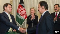 Afghan Trade Minister Anwar Ul Haq Ahadi (left) shakes hands with Pakistani Trade Minister Makdoom Amin Fahim as U.S. Secretary of State Hillary Clinton and Pakistani Prime Minister Syed Yousaf Raza Gillani look on in Islamabad on July 18.