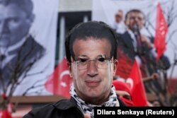 A protester wearing a cutout mask of Istanbul Mayor Ekrem Imamoglu