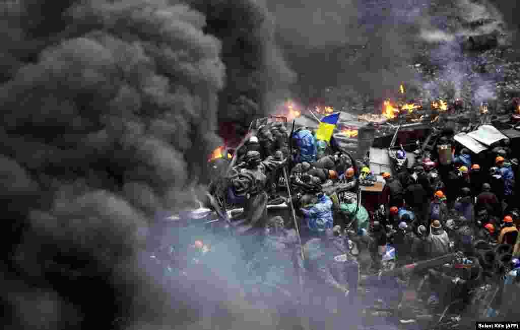 Protesters stand behind burning barricades during a face-off against police in Kyiv on February 20.