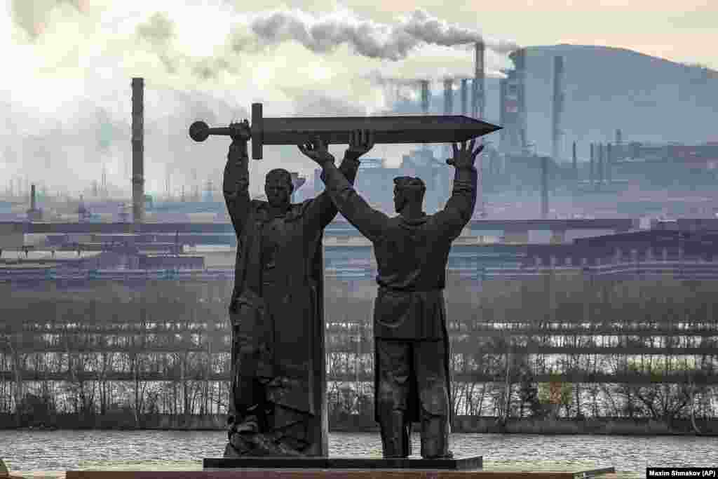 The Rear-Front Memorial in the Russian city of Magnitogorsk. The monument depicts a soldier and a steelworker holding a sword, with the worker facing the vast steel mills that supplied Soviet forces during World War II.