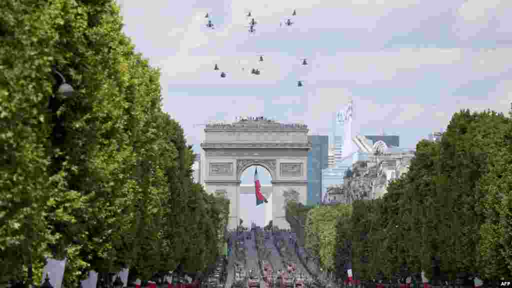 14 iulie 2025 - Elicoptere ale armatei franceze zboară deasupra deasupra Arcului de Triumf și bulevardului Champs-Élysées din Paris, în timpul paradei militare anuale de Ziua Franței.Armata franceză spune că, prin această defilare, a dorit să-şi pună în valoare „credibilitatea operaţională” şi „solidaritatea strategică” cu partenerii săi.„Armata terestră defilează în brigadă bună de luptă, adică gata de luptă”, a afirmat generalul Loïc Mizon, guvernatorul militar al Parisului.