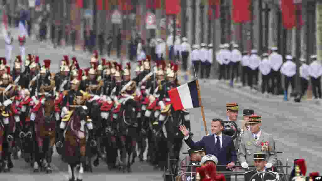 Președintele francez Emmanuel Macron (stânga), șeful Statului Major al Apărării, generalul Thierry Bukhard (dreapta), escortați de Garda Republicană călare în timpul paradei militare de Ziua Bastiliei - Paris, 14 iulie 2025.