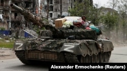 Російські солдати на танку в Попасній на Луганщині з побутовими речами, які, за словами вимушеної переселенки Аліни Коренюк, були викрадені з її будинку. Попасна, 26 травня 2022 року