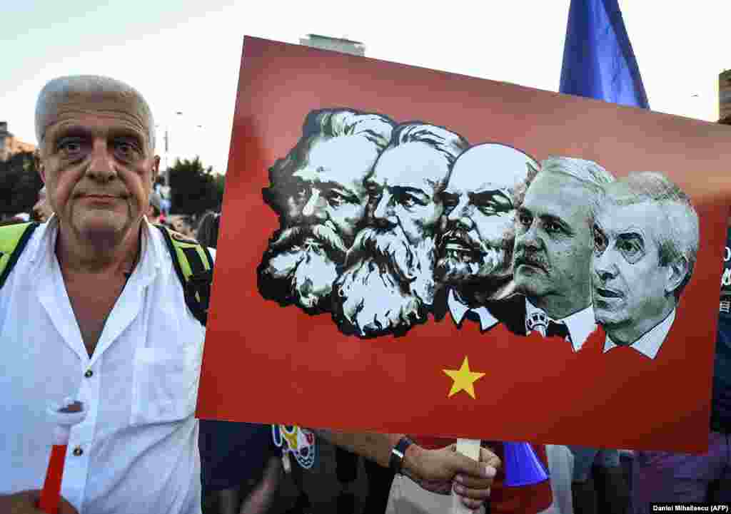 A protester holds a placard depicting Romania's leftist Social Democratic Party leaders in a lineup of Communist icons.