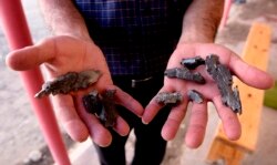 A man shows artillery shell fragments in the village of Agdam in the Tovuz district near the Azerbaijani-Armenian border on July 15.