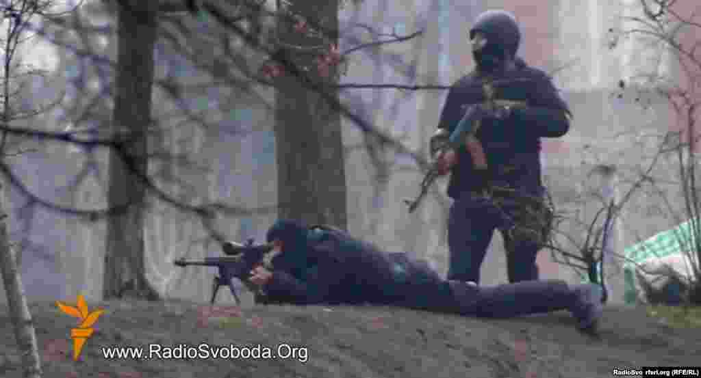 A still photo from a video by RFE/RL's Ukrainian Service shows Ukrainian security personnel with a Kalashnikov assault rifle and sniper rifle in a confrontation with protesters in Kyiv on February 20, 2014. Dozens of protesters are believed to have been killed by gunfire on this day.
