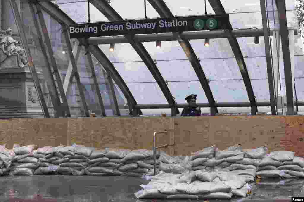 A New York Police officer guards a closed subway entrance in downtown Manhattan as Hurricane Sandy makes its approach in New York. 